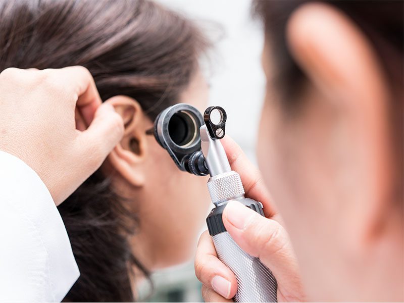 Audiologist examining ear with an otoscope